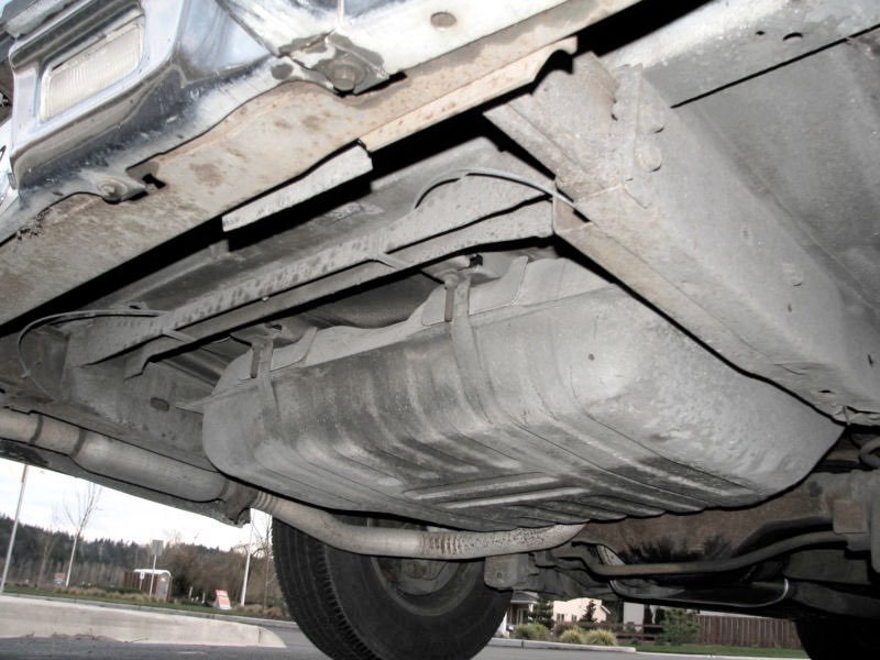 View of the underside of a vehicle showing the fuel tank and part of the exhaust system.