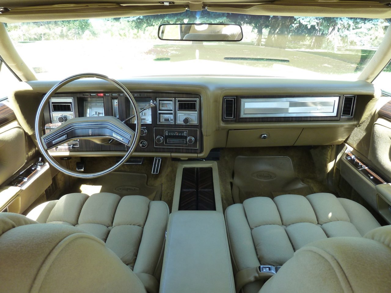 Interior view of a vintage car dashboard with beige upholstery and classic controls