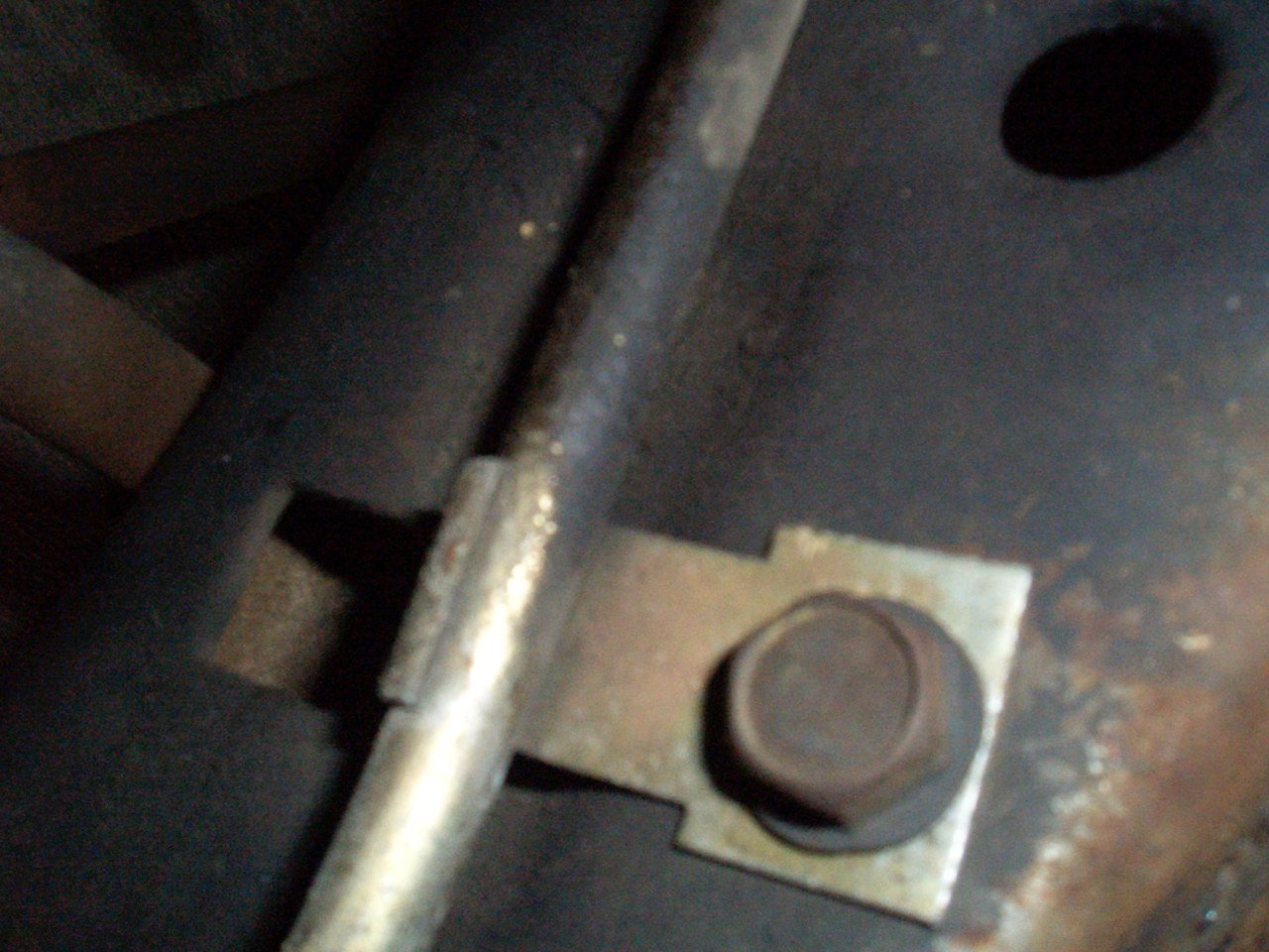 Close-up of a metal hinge and bolt on a dark machine or industrial equipment.