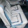A close-up of a car seat with light-colored upholstery and blue accents.
