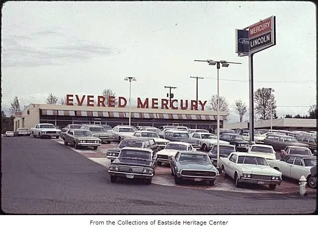 Vintage car dealership with a large sign reading 'Everd Mercury' and a smaller sign for Lincoln, showcasing a parking lot full of classic cars.