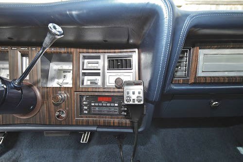 Close-up of the dashboard in an older model vehicle with various controls, an air freshener, and a CB radio.