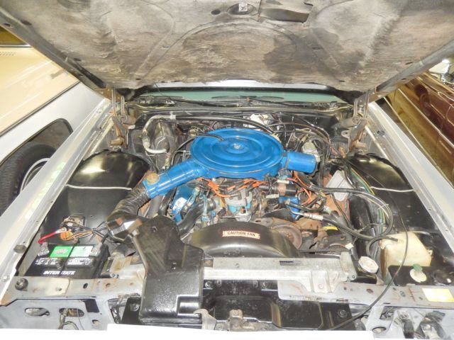 Car engine with a blue air cleaner, various hoses, wires, and components under the hood.