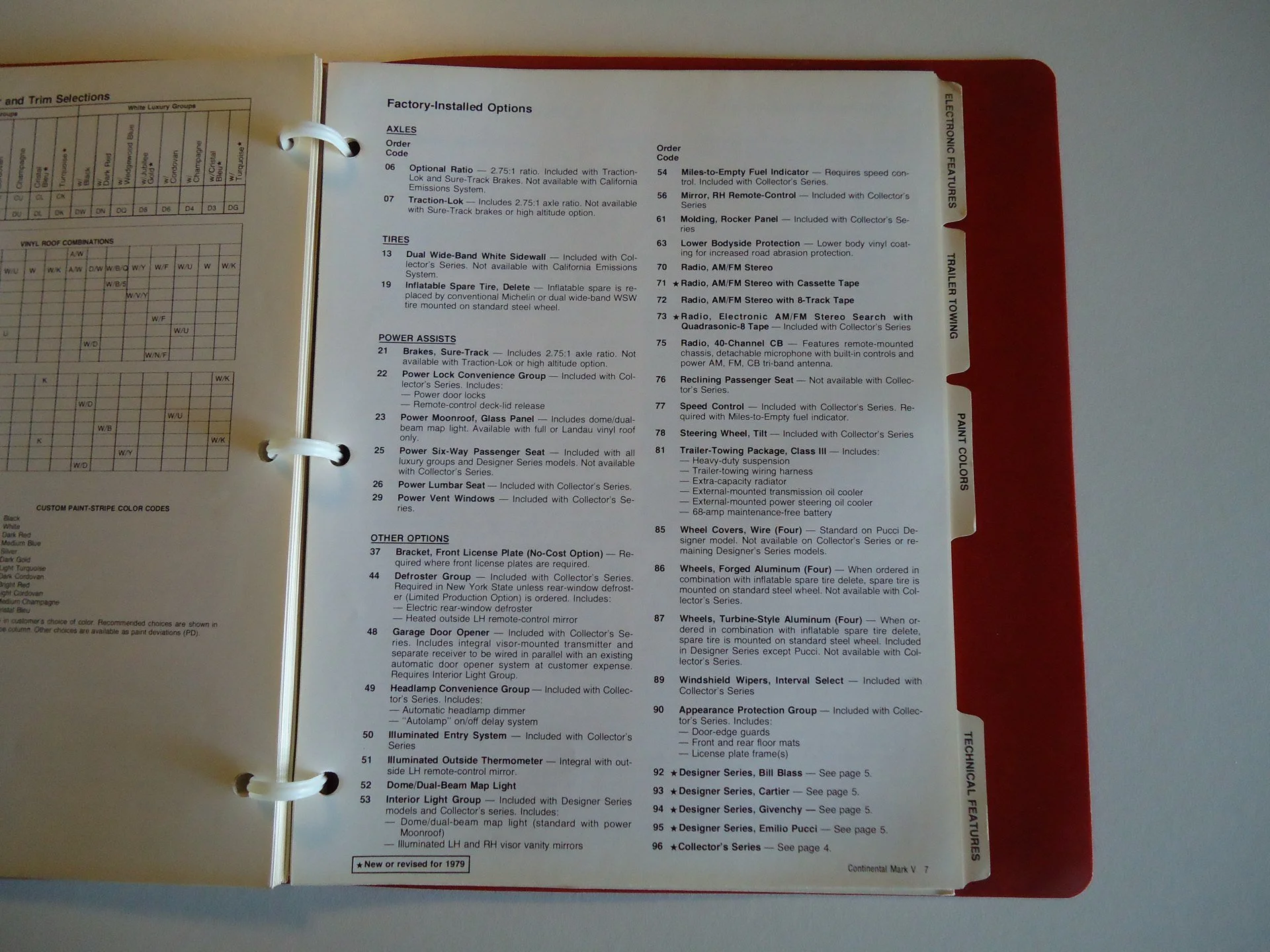 Open car brochure or manual showing factory-installed options for a vehicle, including tires, power assists, optional features, and technical features, in a binder with a red cover.