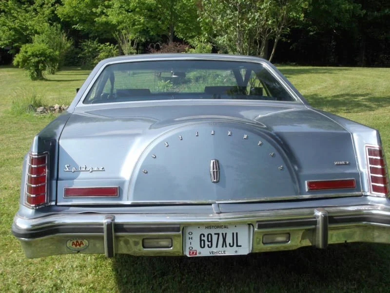 Rear view of a vintage Lincoln Mark V automobile with a spare tire cover reading 'Lincoln' and a Canadian license plate.