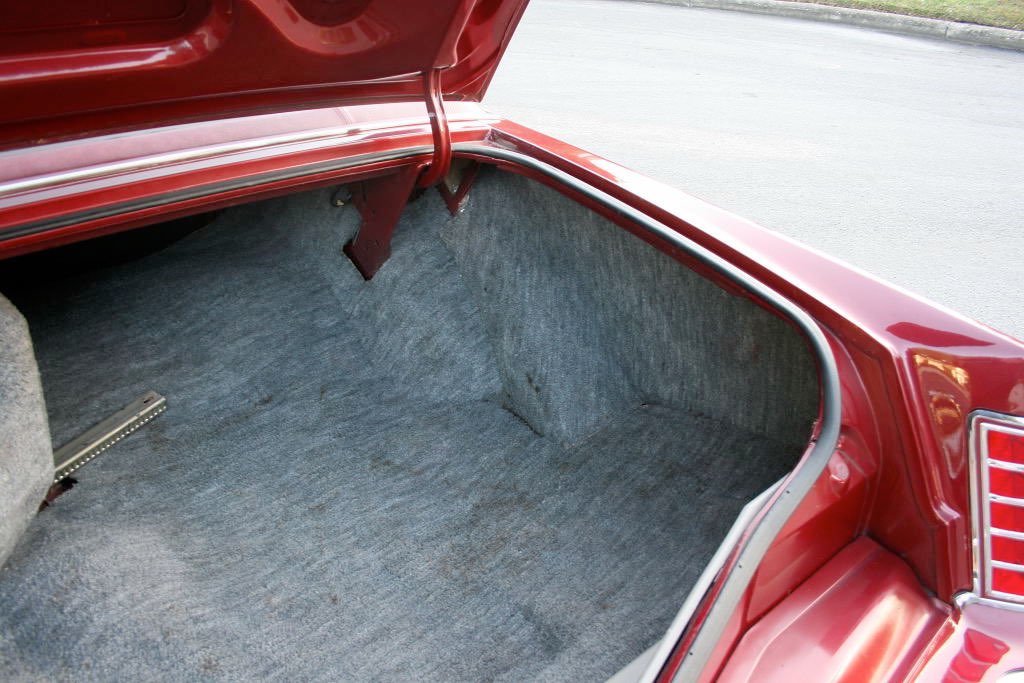 Empty car trunk with gray carpeting and red exterior.