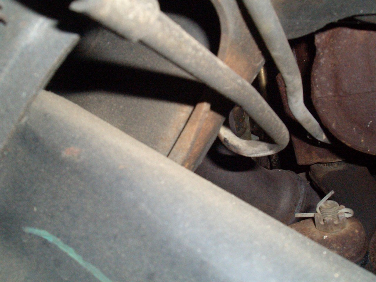 Close-up of an engine with visible metal pipes, bolts, and rusted parts.