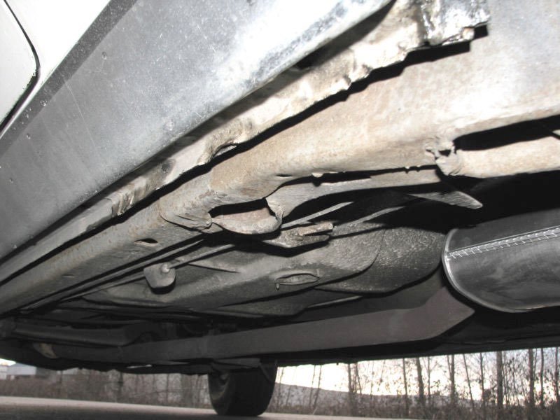 Underneath view of a vehicle showing damaged or bent exhaust pipe and underside components.