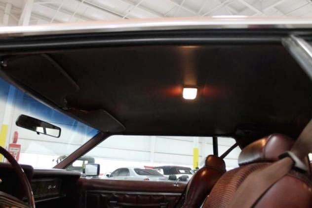Interior of a car with a drop ceiling and a small interior light, parked in a parking lot.