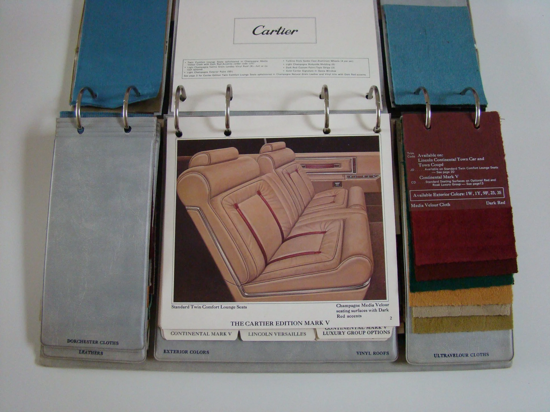Color sample booklet with fabric swatches, sample color options, and a catalog page for luxury car interior upholstery, featuring a leather sofa with red accents.