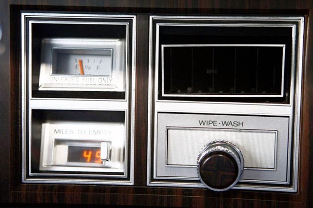 Vintage car dashboard with fuel gauge, mileage display, empty fuel warning, and a wipe-wash control knob