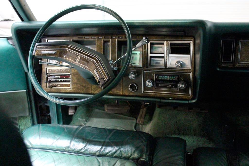 Interior dashboard of a vintage green truck with steering wheel, gauges, and radio.