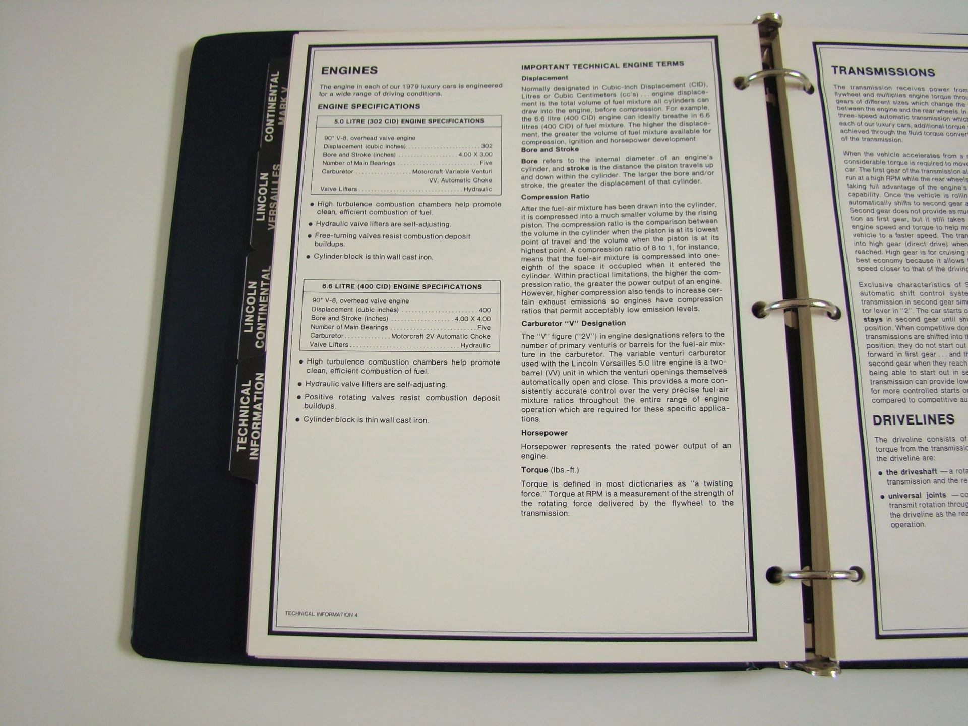 Open binder with technical car engine information pages, including sections on engines, transmissions, and drivelines, with black side tab labeled 'Lincoln Continental Versaille'.