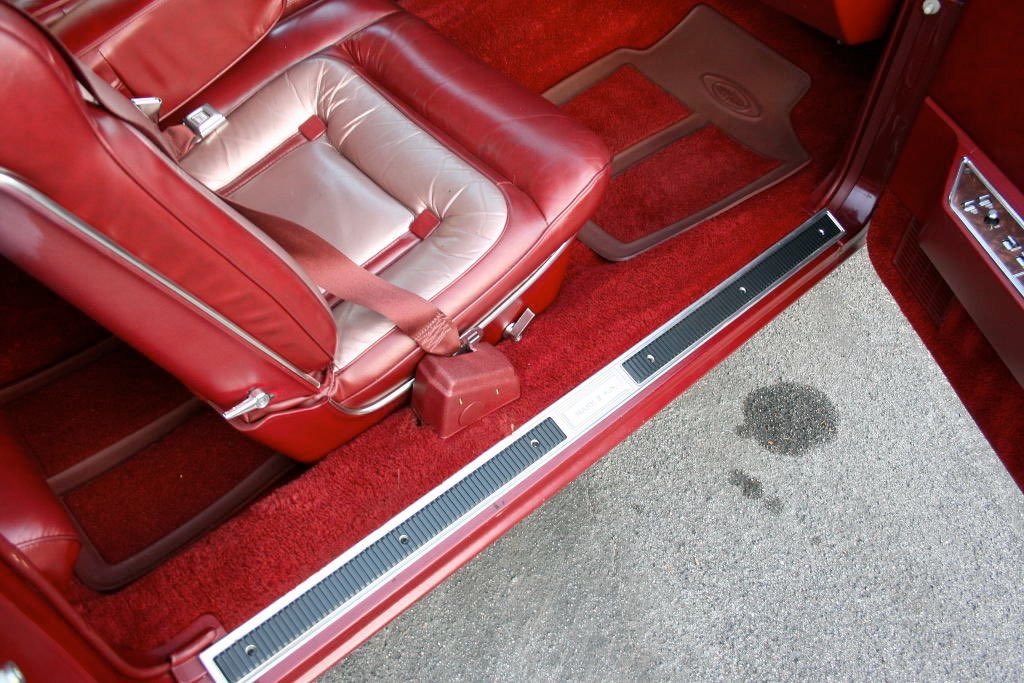 Interior of a vintage red car showing red leather seats, red carpet, and part of the dashboard