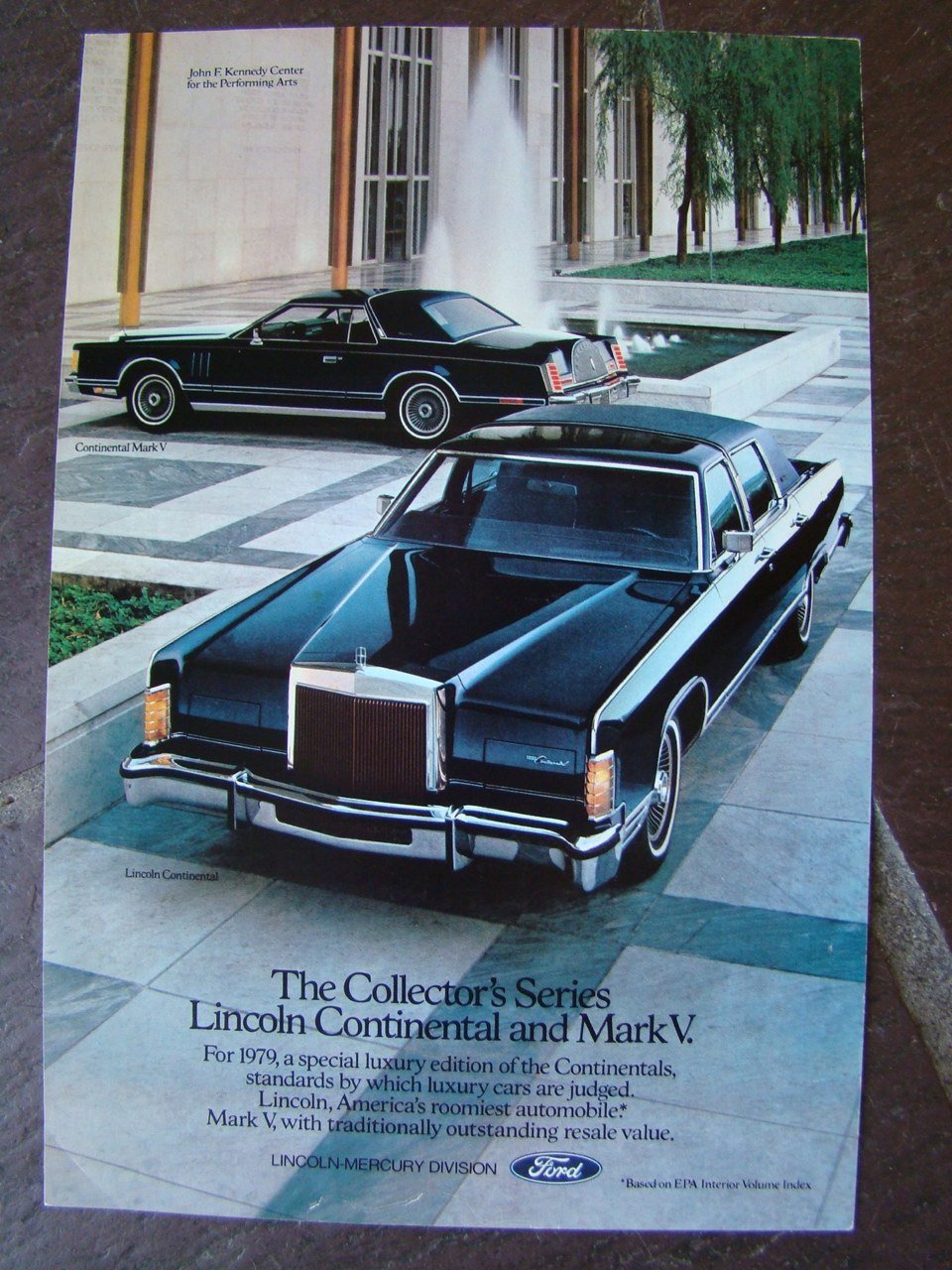 Promotional flyer displaying two vintage luxury cars, the Lincoln Continental and Mark V, parked outdoors near a modern building with glass windows and a fountain. The flyer mentions the Lincoln Continental Mark V and the Lincoln Continental as part