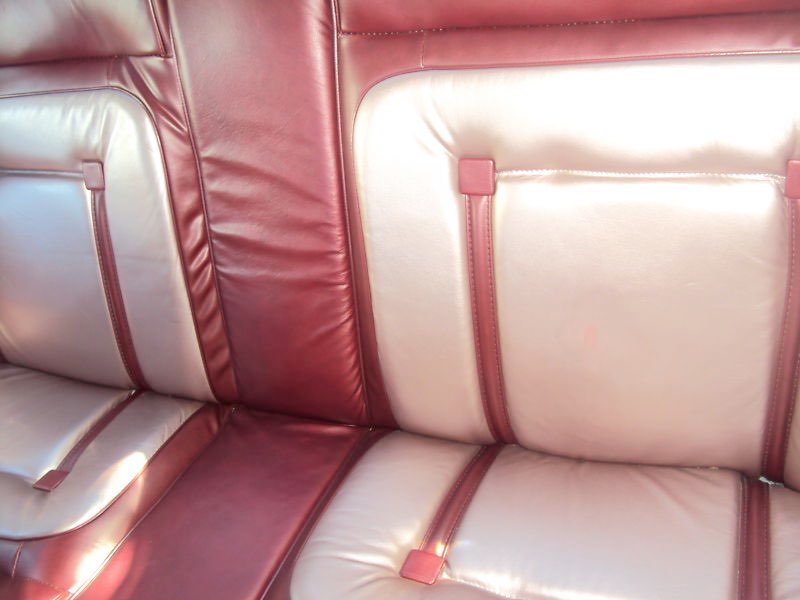 Close-up of pink and white leather car seats with zippers and padding.