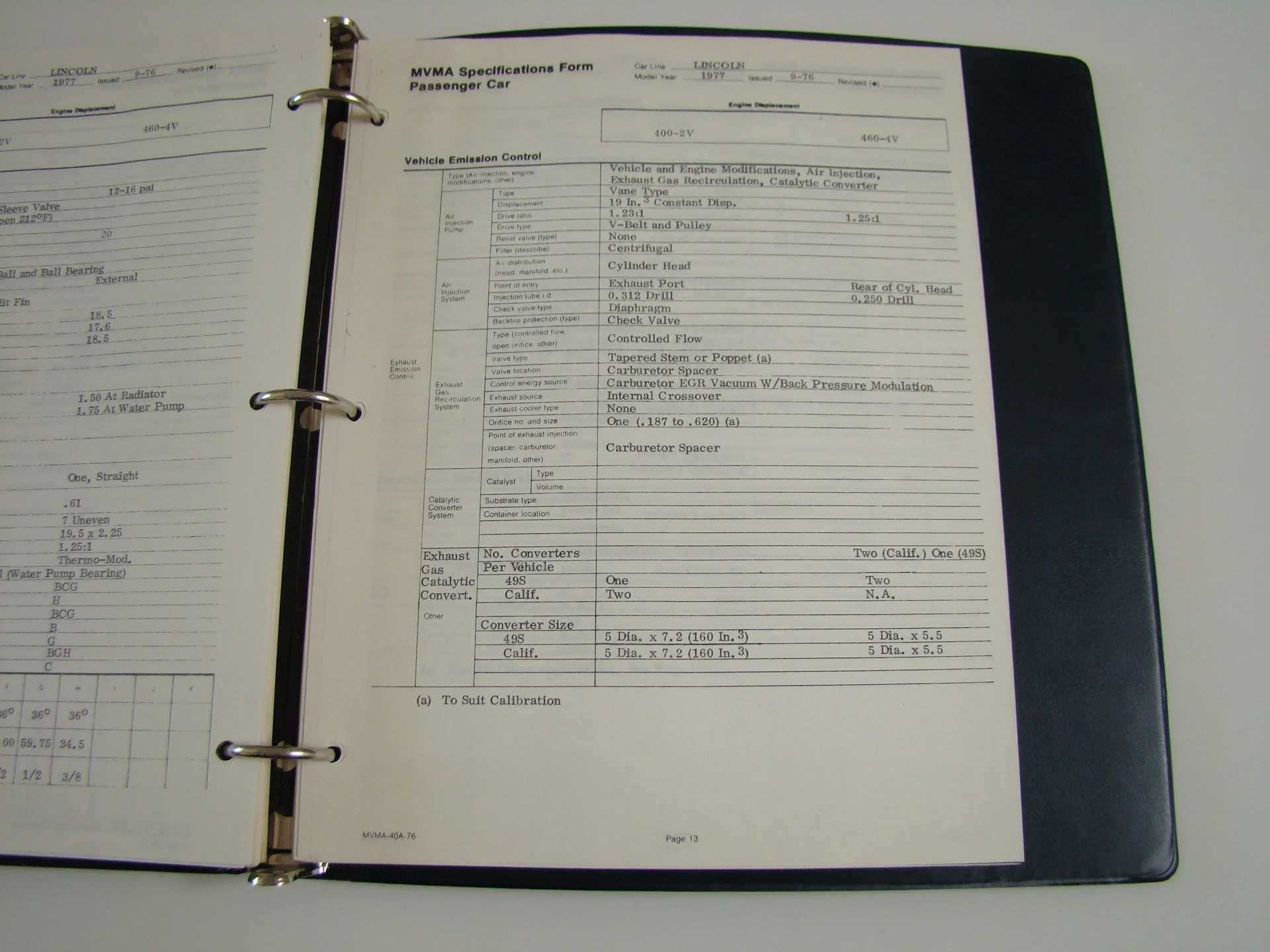 Open binder containing a vehicle emission control specifications form for a 1977 Lincoln passenger car.