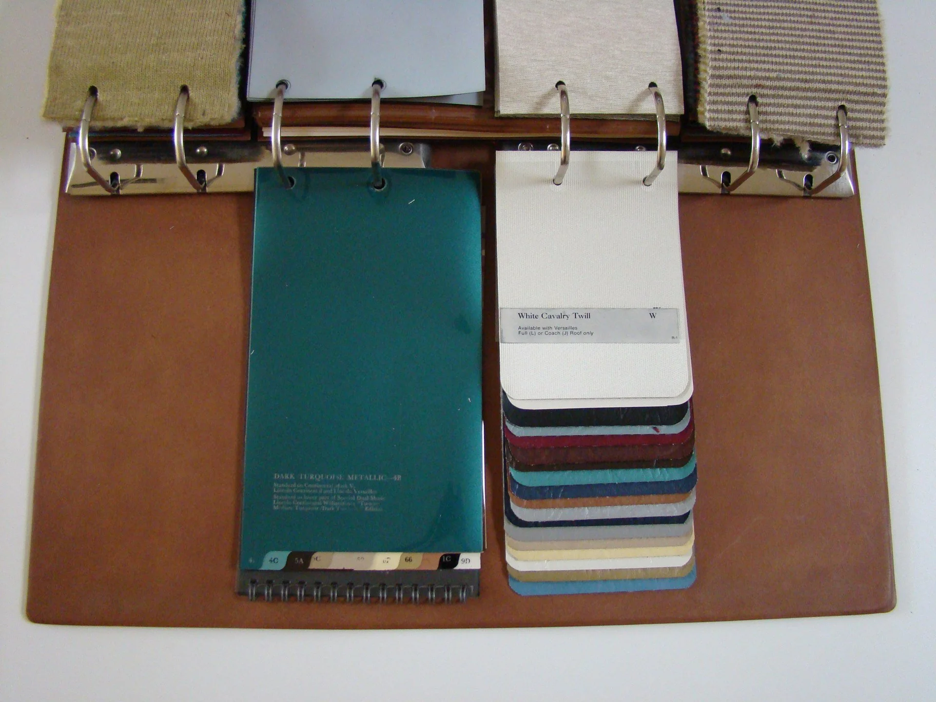 A display of fabric swatches, paint color samples, and color card samples on a brown mat for interior design or decorating purposes.