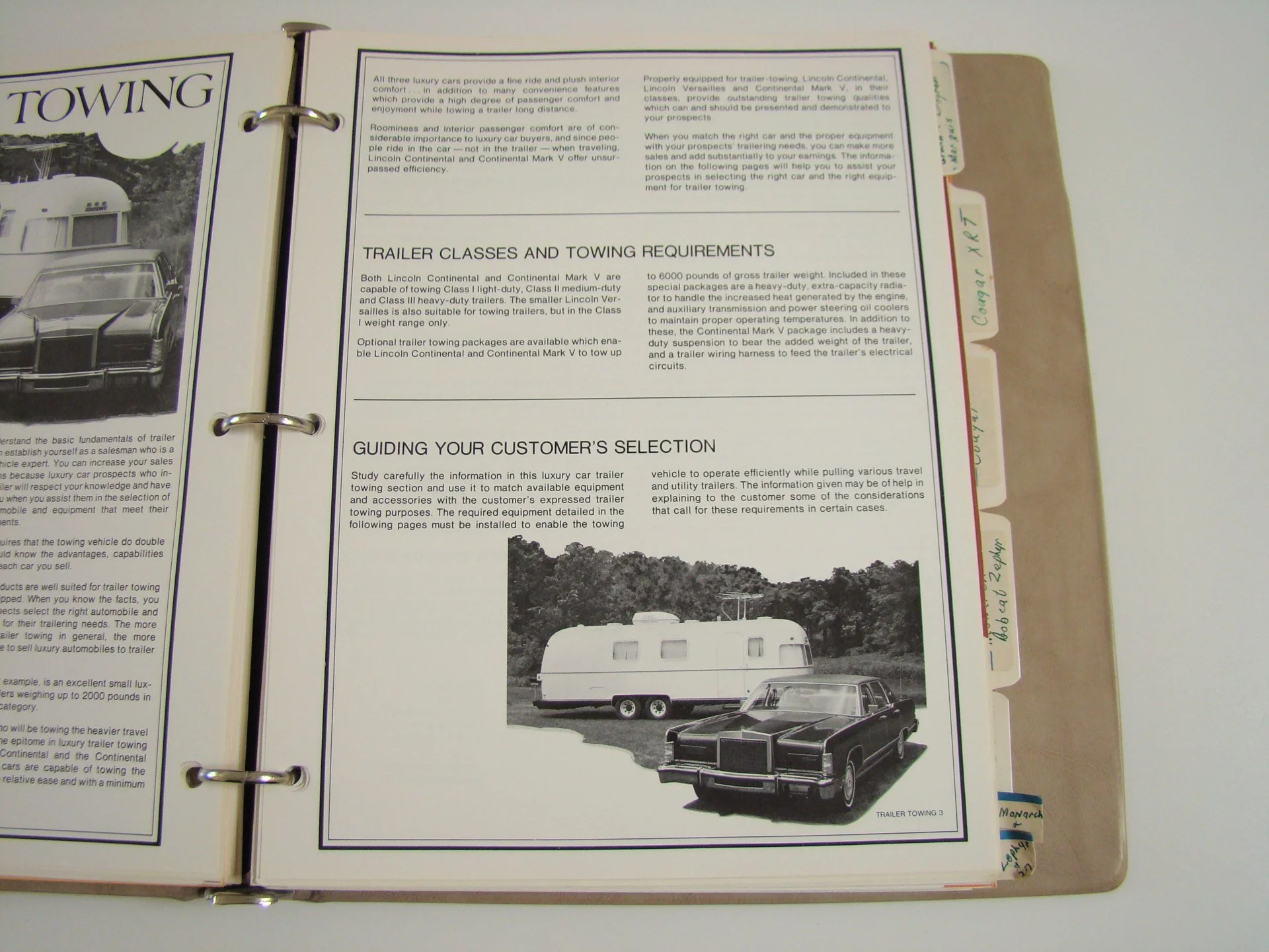 Open binder with pamphlet about trailer classes and towing requirements, featuring black and white photos of a trailer and a car.