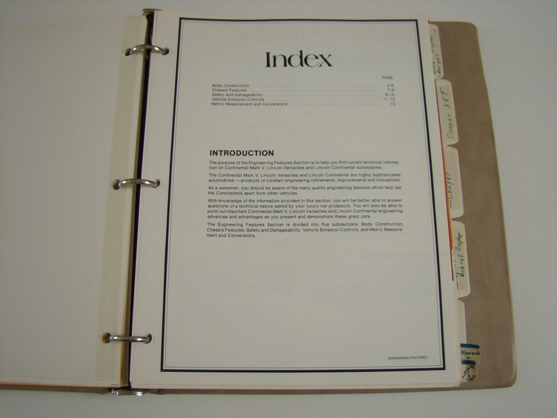 Open binder with paper titled 'Index' displaying sections on vehicle engineering features, with handwritten tab labels on the right side.