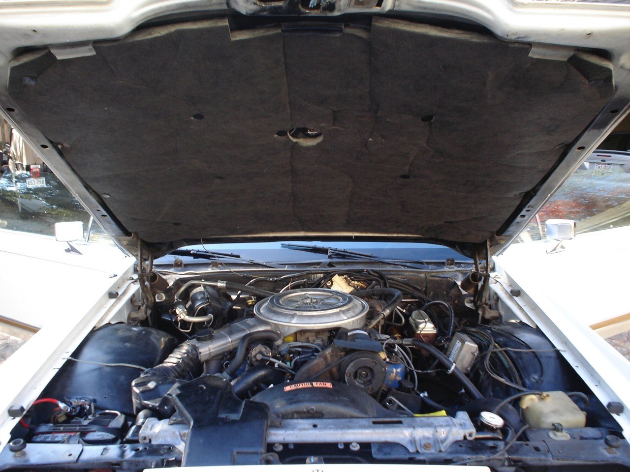 Under the hood of a car showing engine components and wiring.