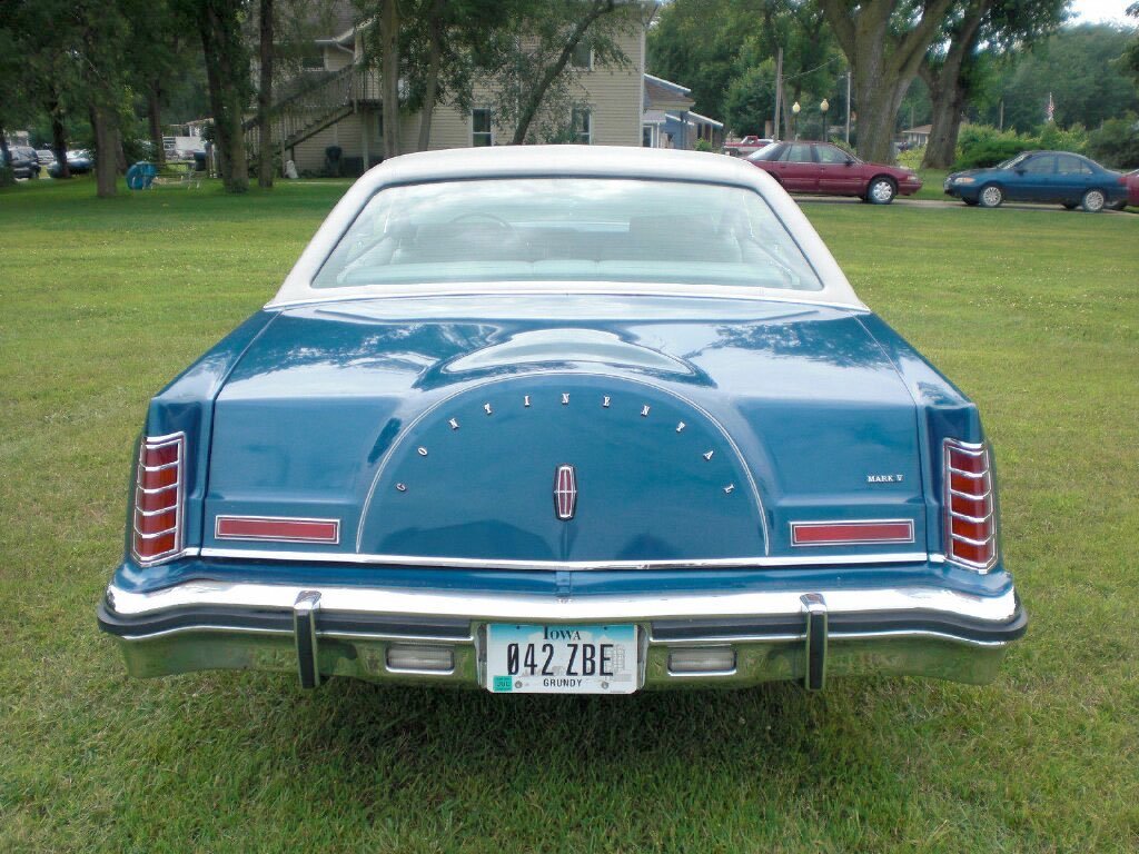 Rear view of a vintage blue and white Lincoln Mark V car parked on grass, with Iowa license plate reading 042 ZBE.
