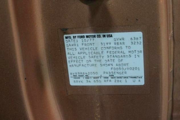 Vehicle identification and manufacturing label on a car door frame, showing manufacturing details, specifications, and safety standards.
