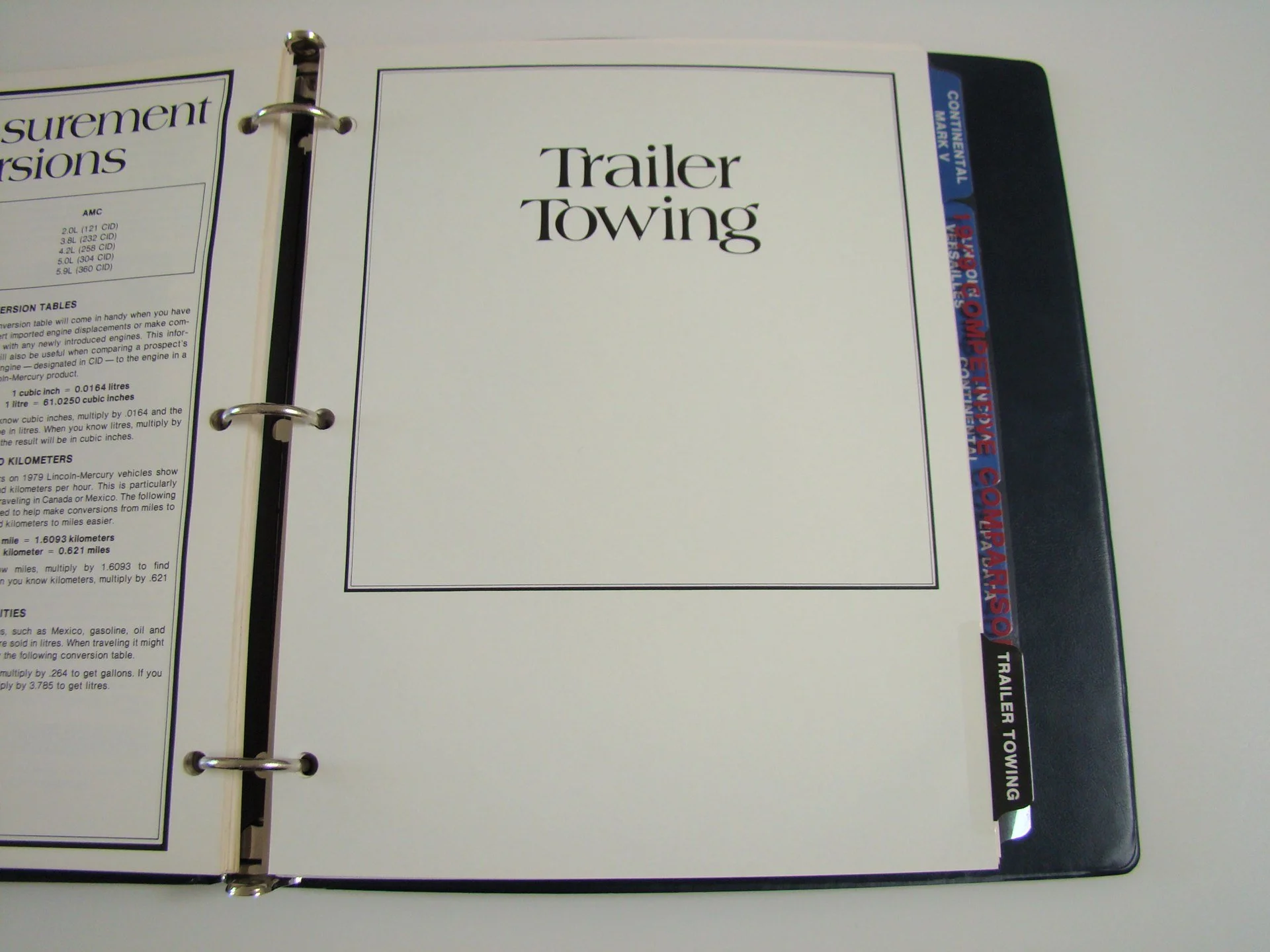 Binder open to a booklet titled 'Trailer Towing' with a tab on the right labeled 'Trailer Towing' and another tab with 'Continental Mark V' and 'Companion / Passo' with a black cover.