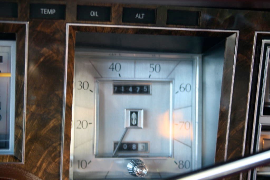 Close-up of a vintage car dashboard with a speedometer, odometer, and control buttons labeled "TEMP," "OIL," "ALT."