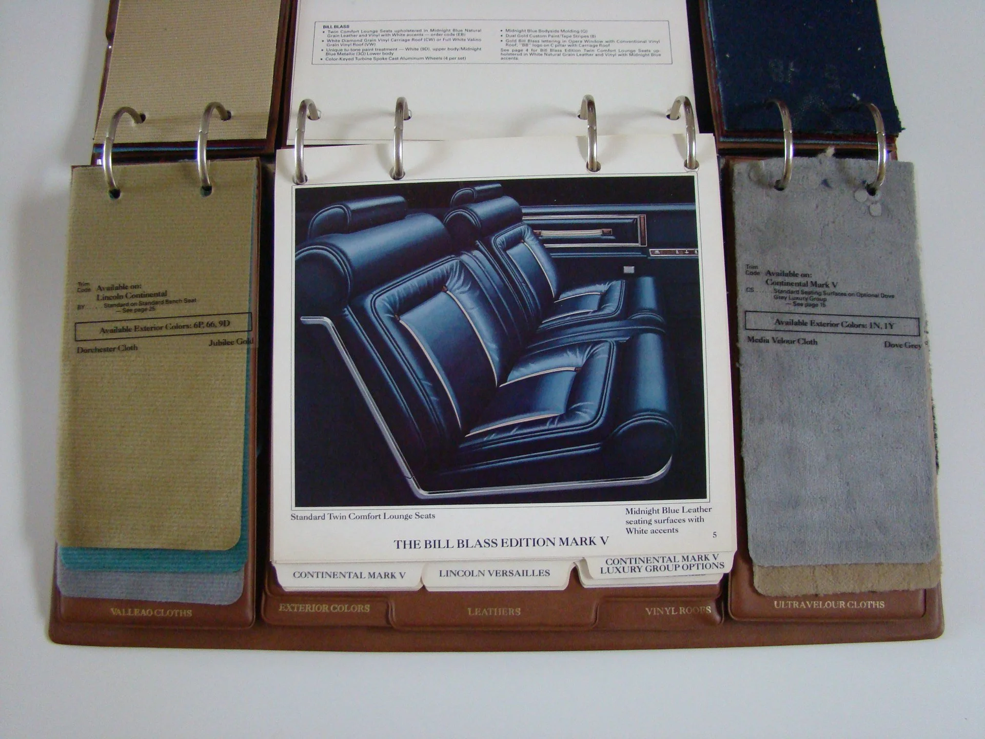 Car interior material sample book open to a page showing navy blue leather car seats and a close-up photo of the seats.