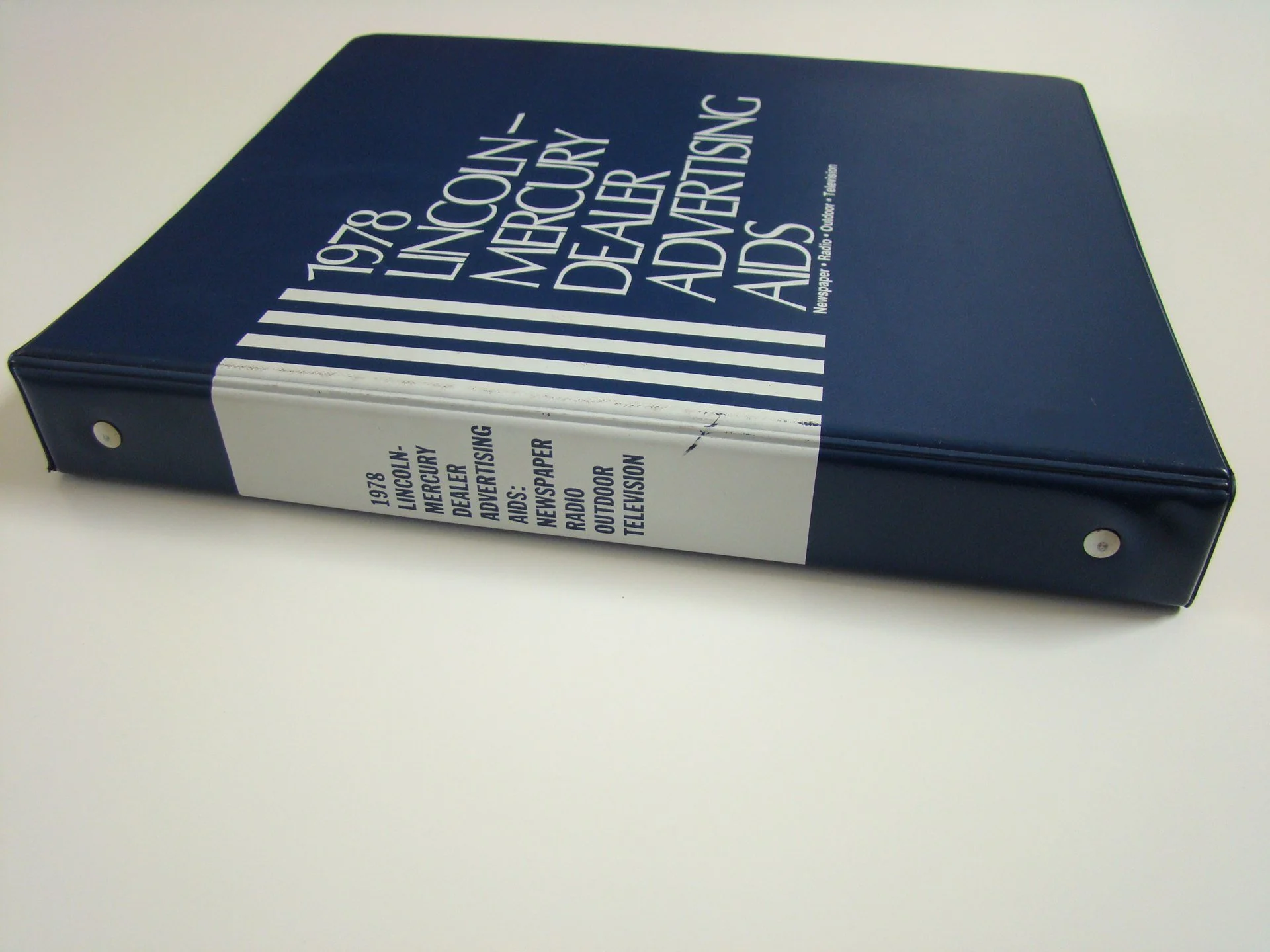 Book titled '1978 Lincoln-Mercury Dealer Advertising' on white surface.