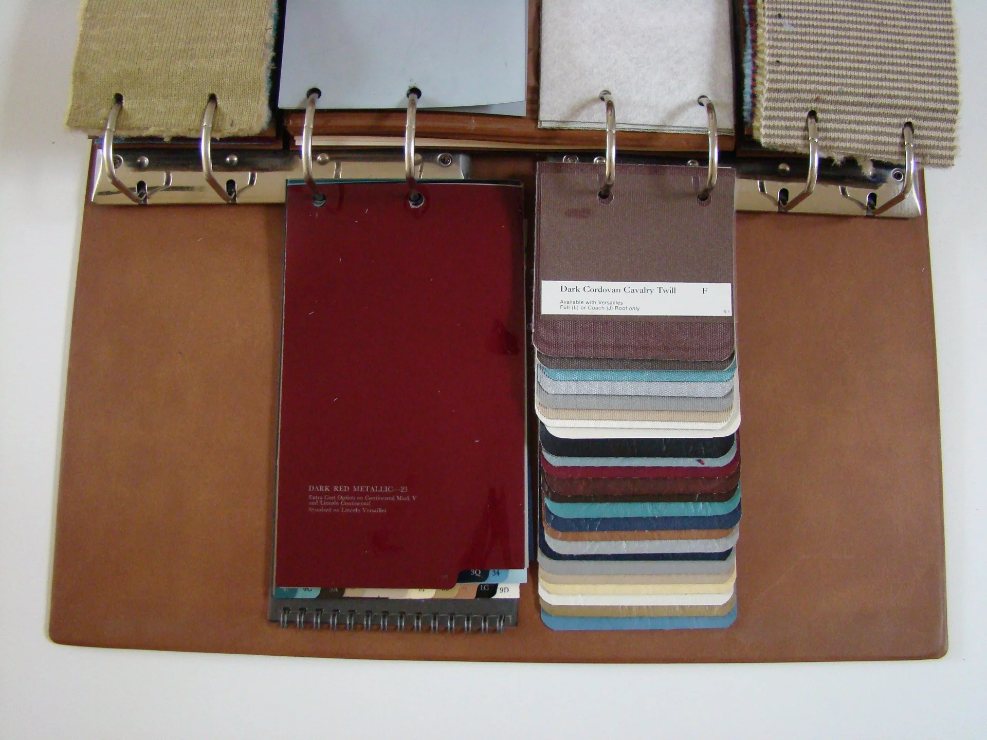 Color swatches and fabric samples displayed on a board, including a red metallic sample and a stack of fabric swatches in various colors and textures.