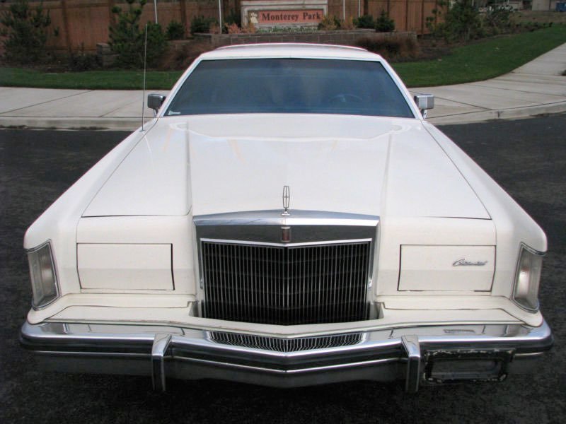 Front view of a vintage white Lincoln Continental car parked on a street in front of a park sign that reads Monterey Park.