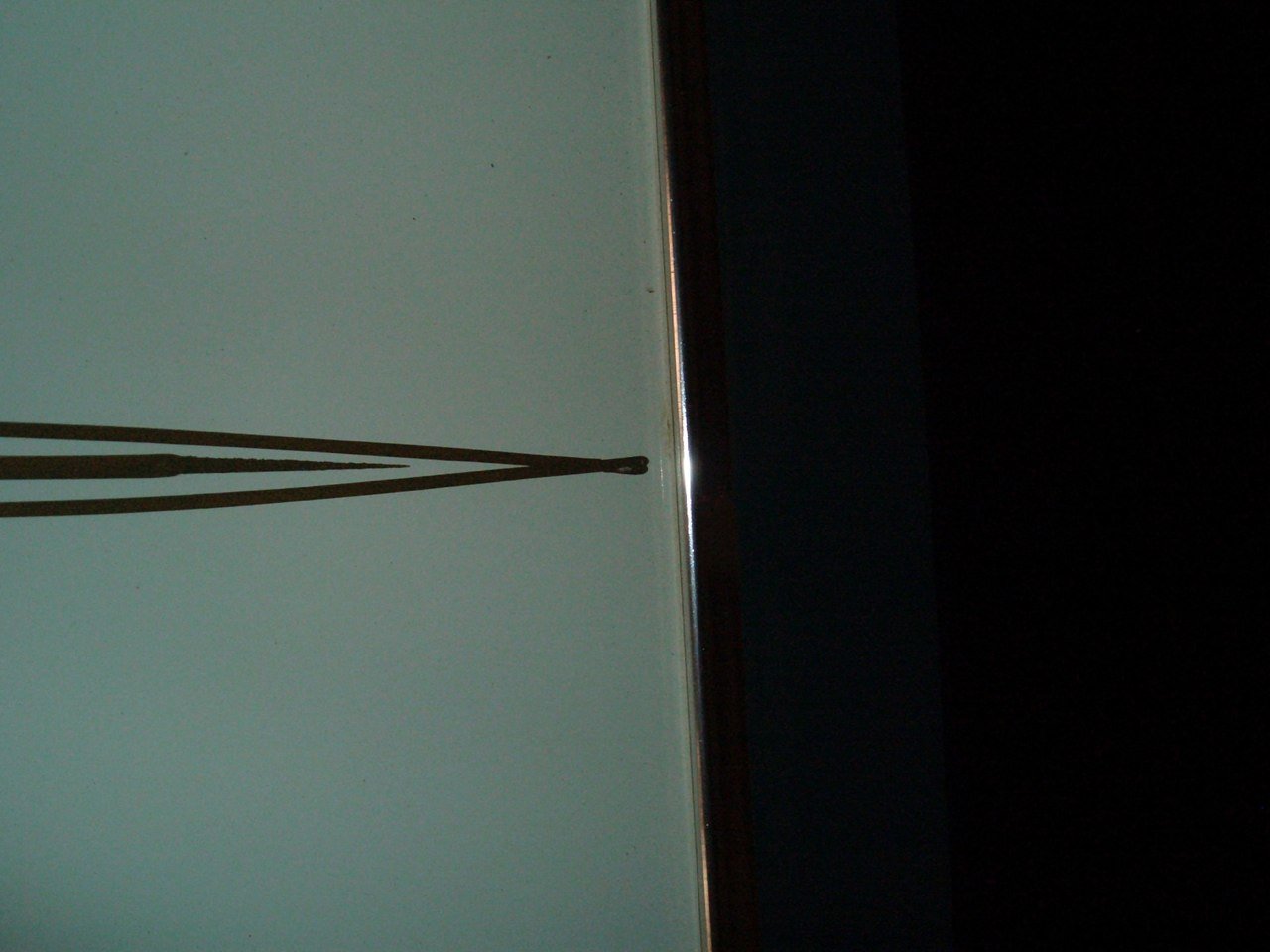 Close-up of a computer monitor or television screen showing a white background with a small black dot. The screen has a narrow black bezel along the right edge. The image is rotated 90 degrees clockwise.