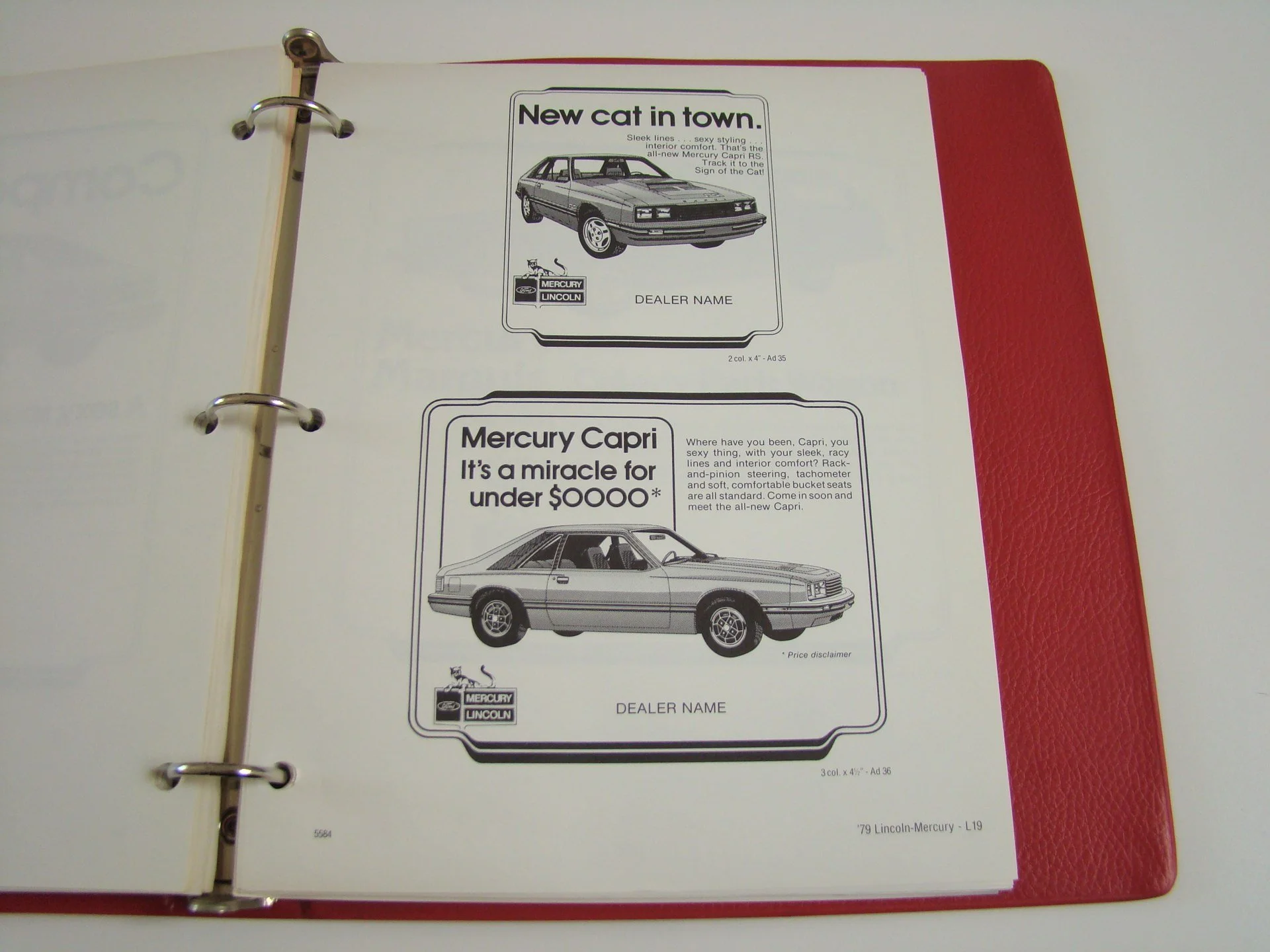 A binder with pages displaying two car advertisements for Mercury Lincoln cars. The top ad features a sleek car with the headline "New car in town." The bottom ad shows a Mercury Capri with the headline "It's a miracle for under $0000*" and a descrip
