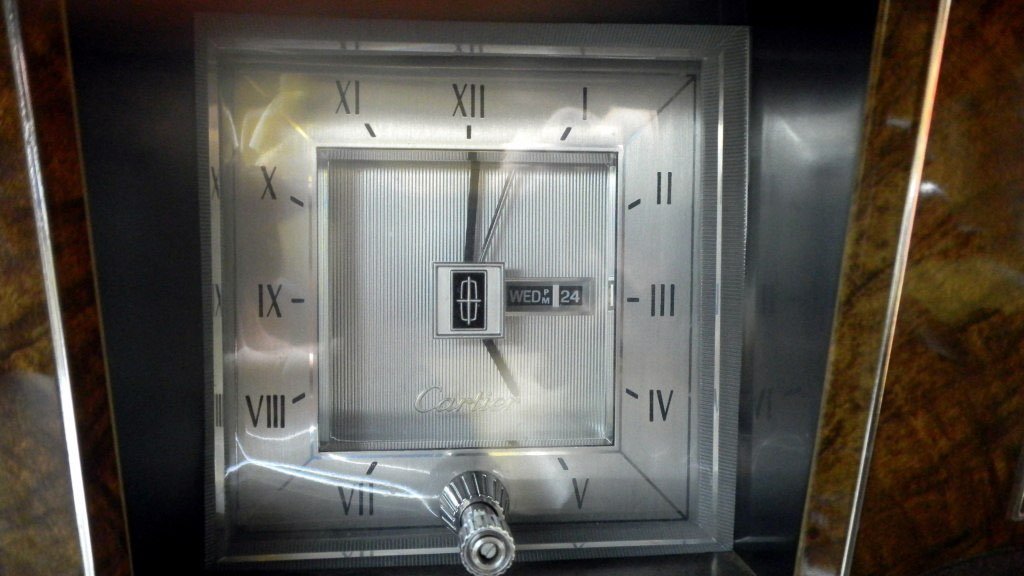 Close-up of a vintage Carrera clock with Roman numerals, showing the time as 4:00, with a metallic finish and a small digital display indicating the date as Wednesday, the 24th.
