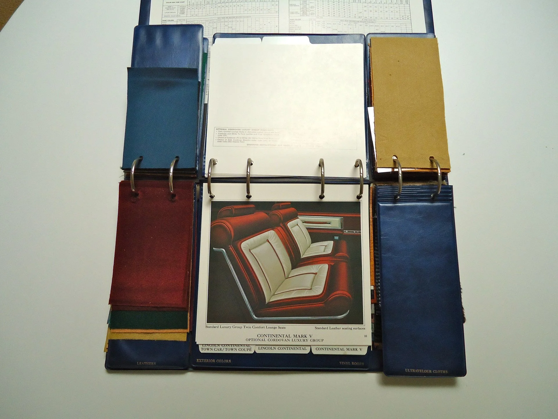 Color swatch and material sample book featuring fabric, leather, and vinyl options for car interior upholstery.