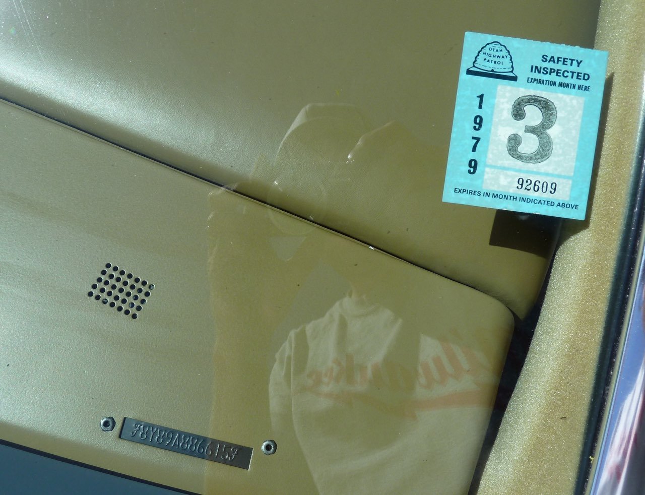 A close-up view of a vehicle's dashboard showing a blue Utah Highway Patrol safety inspection sticker with the year 1979 and the number 3, along with an ODM serial number and a small vent hole.