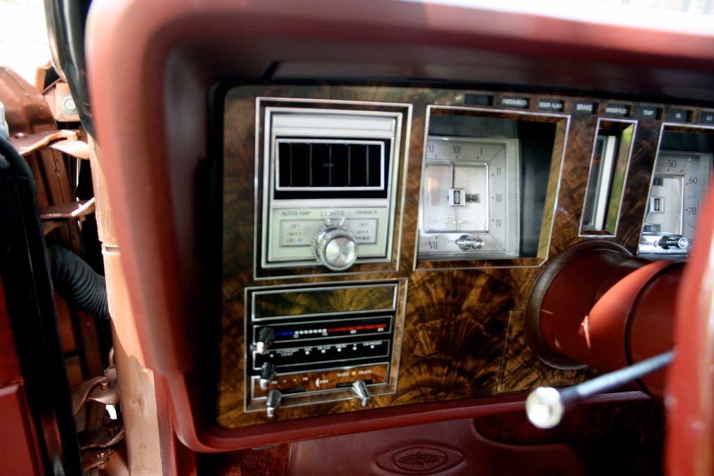 Close-up of a vintage car dashboard with wood paneling, gauges, and controls.