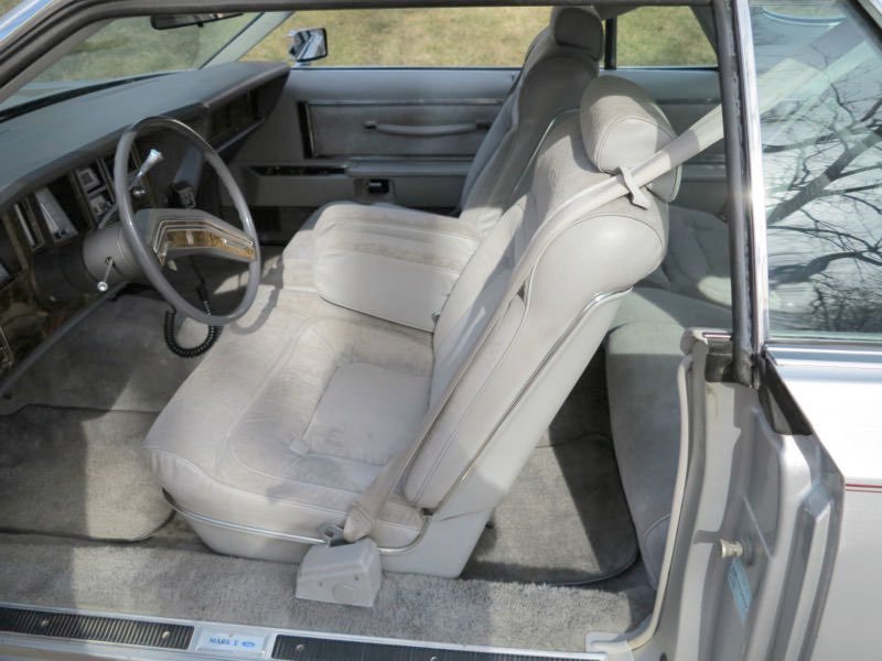 Interior of a vintage car showing the front passenger and driver seats, steering wheel, and dashboard.