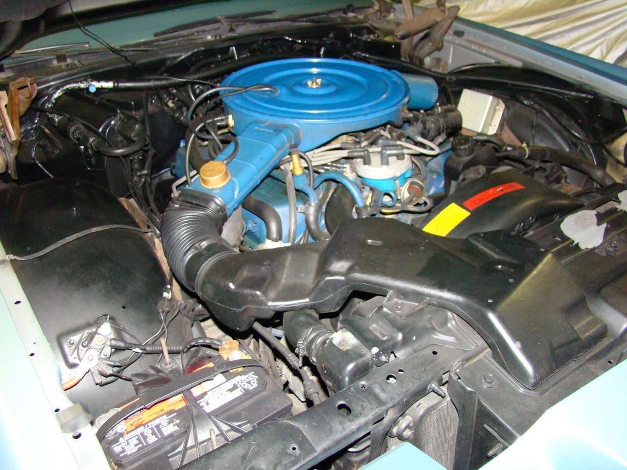 Car engine with blue air cleaner and black radiator cover.