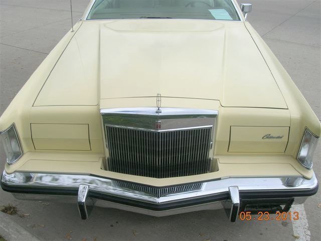Front view of a vintage cream-colored car, likely a 1970s Mercury Cougar, parked on a concrete surface.