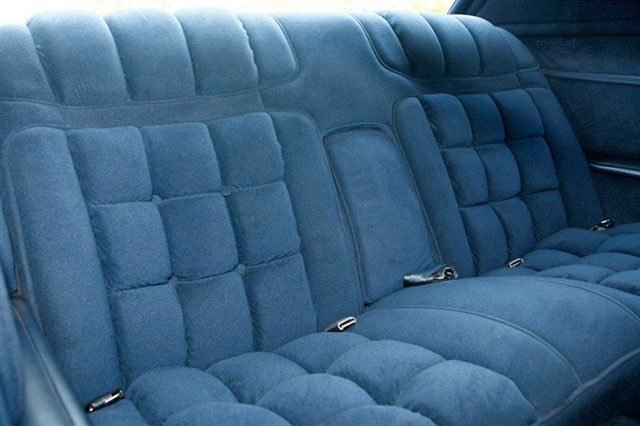 Blue upholstered car backseat with quilted pattern and seat belts