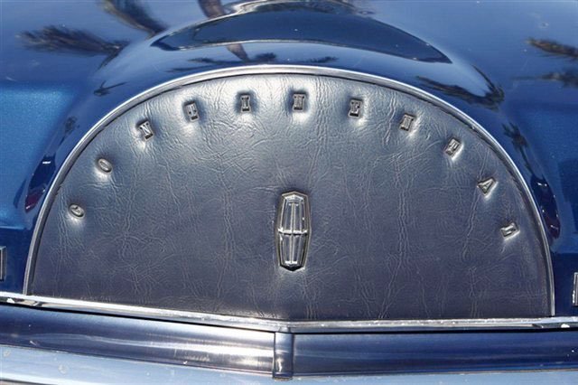 Close-up of a vintage car's dashboard with a leather speedometer, featuring the Lincoln logo at the center.