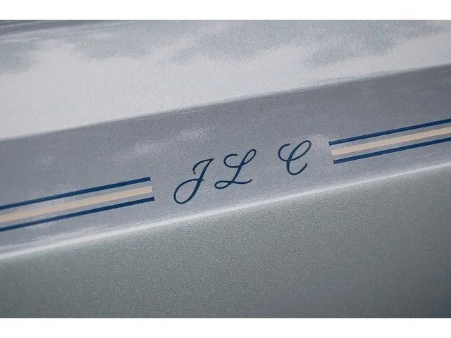 Close-up of a car's hood with the initials 'JLC' and decorative blue stripes.