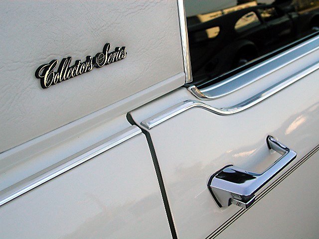 Close-up of a vintage white car door with chrome handle and a badge that reads 'Collector's Series.'