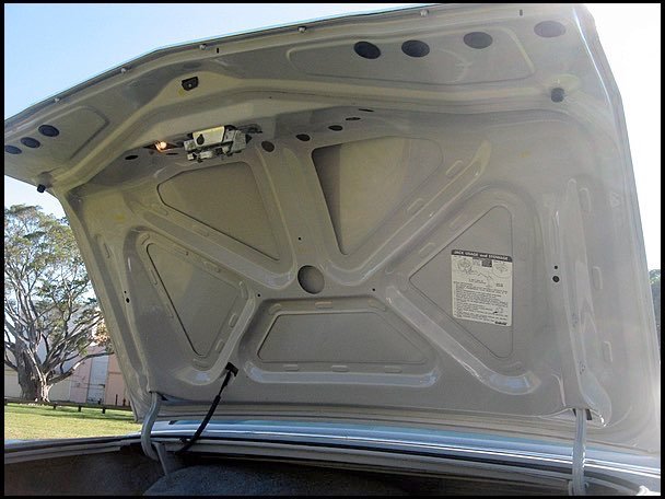 Close-up of the underside of a car's open trunk lid showing the structure and mechanisms.