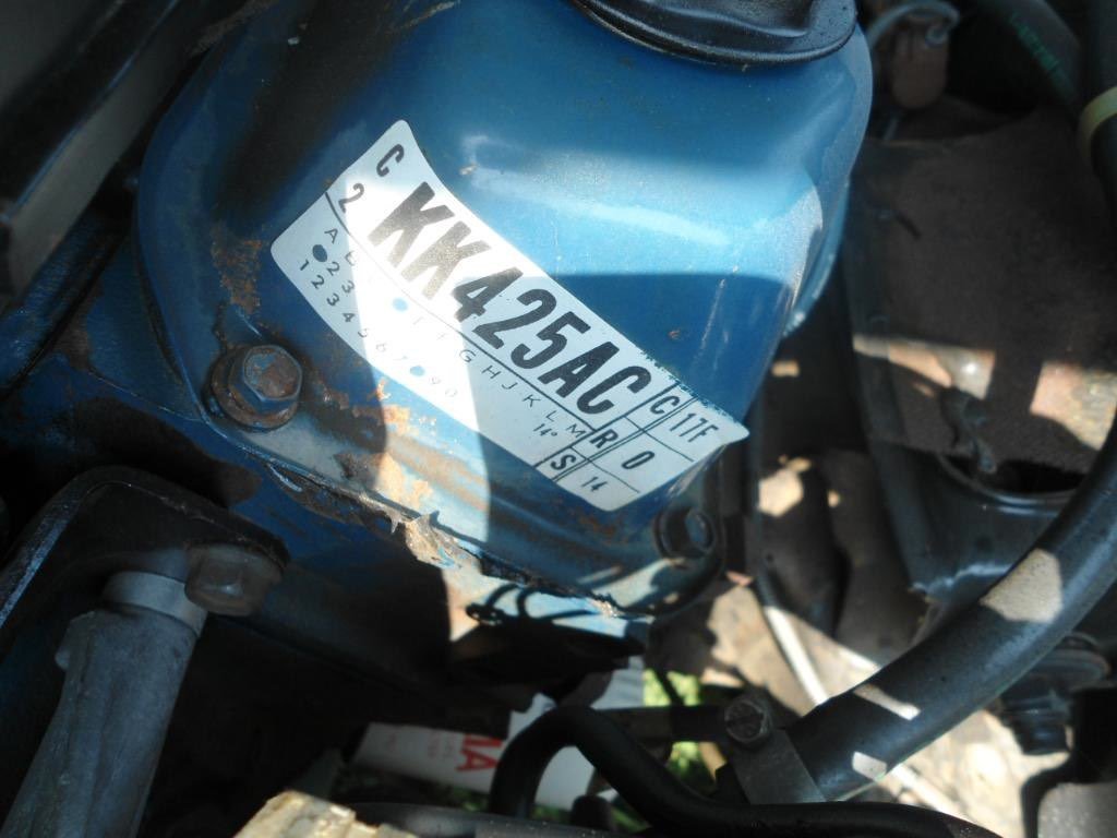 Close-up view of a blue engine component with a white vehicle identification number (VIN) sticker.