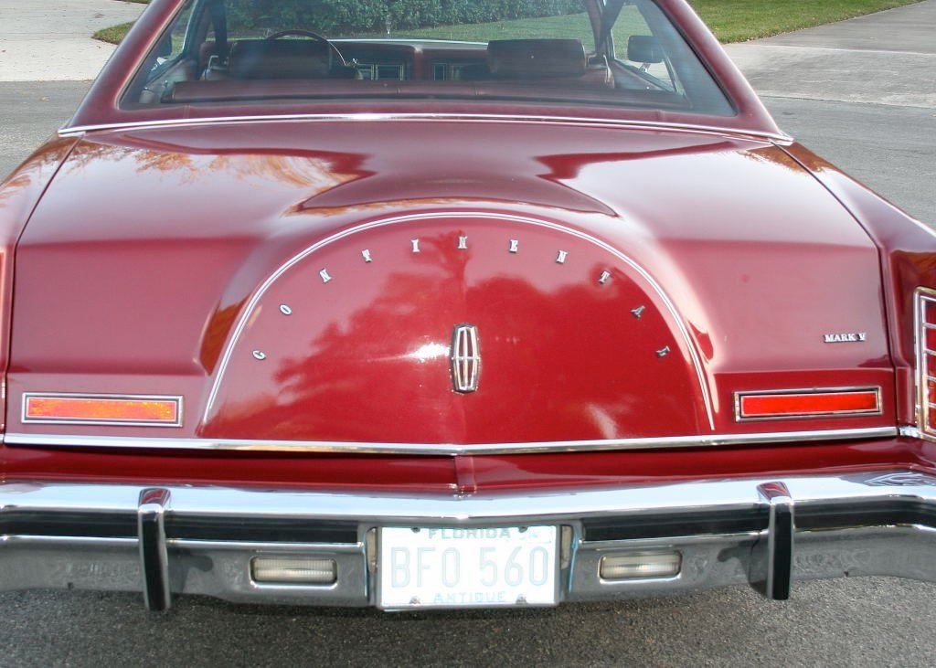 Rear view of a vintage red Lincoln Mark V car with an ornate trunk lid and Florida license plate.