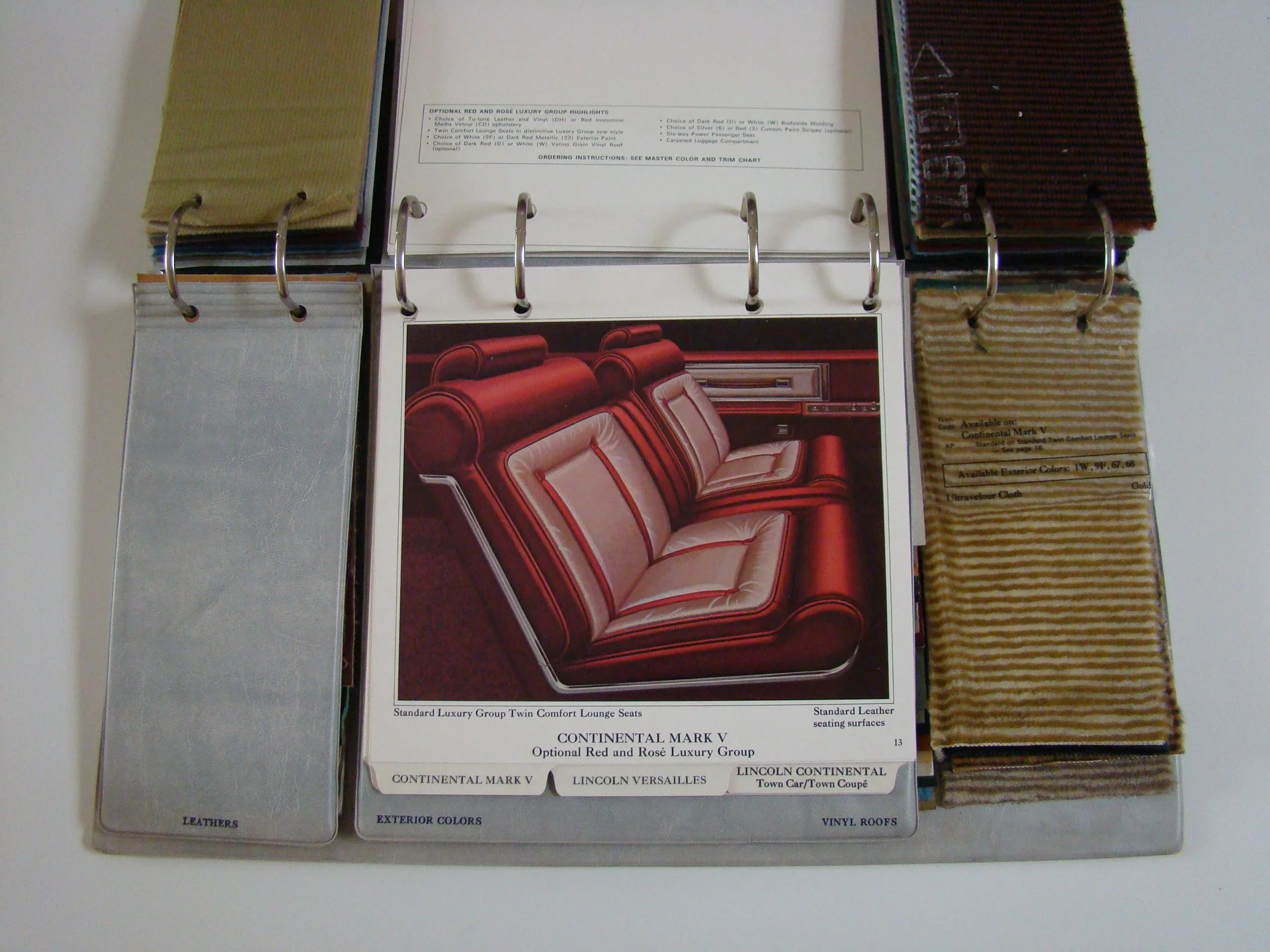 Open car interior fabric and color sample book with a page displaying a red and beige luxury car seat design.